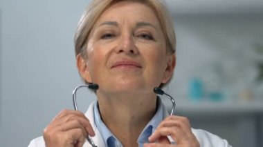 Deneyimli bayan doktor steteskop takıyor ve kameraya bakıyor.