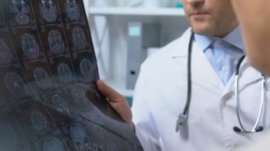 İki doktor röntgen sonuçlarına bakıyor, hasta semptomları ve teşhisleri tartışıyorlar.