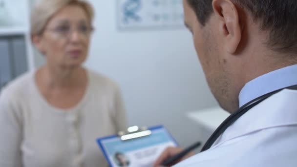 Médico masculino verificando paciente feminino formulário de história médica, exame de saúde — Vídeo de Stock