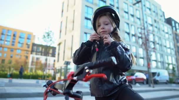 Kleines Mädchen fixiert Schutzhelm und fährt Fahrrad auf der Straße, Sport und Hobby — Stockvideo