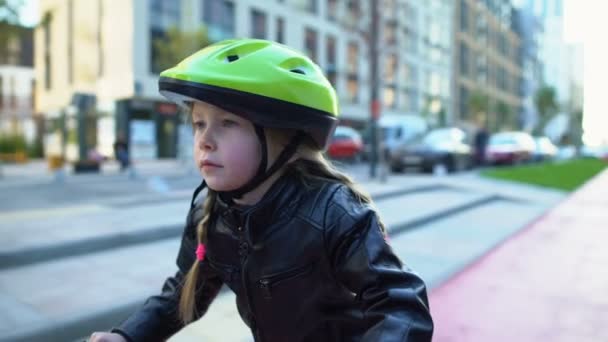 Lindo niño femenino en casco de seguridad sentado en bicicleta, listo para montar en la calle — Vídeo de stock