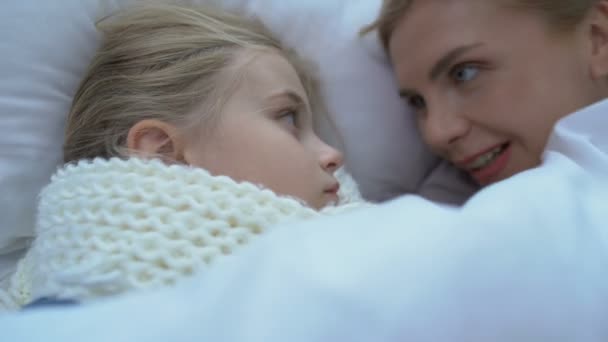 Mãe deitada perto pequena filha doente em cachecol, criança de apoio, aperto ou gripe — Vídeo de Stock