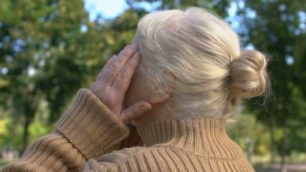 Зрелая женщина страдает мигренью на открытом воздухе массажные храмы, здравоохранение, напряженность — стоковое видео