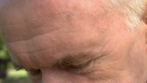 Радісний старий дивиться на камеру на відкритому повітрі, розмитий зір, проблема з зором — стокове відео
