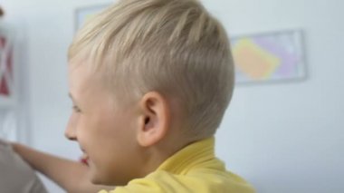 Hoş, gülümseyen bir çocuk. Annesine sarılıyor, sevgi ve ilgi gösteriyor. Sıcak bir aile ilişkisi.