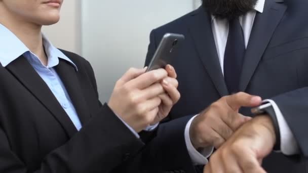 Manažerka scrolling smartphone venkovní, mužský kolega ukazuje na hodinky — Stock video