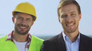 Mutlu erkek müşteri ve müteahhit kameraya gülümsüyor.