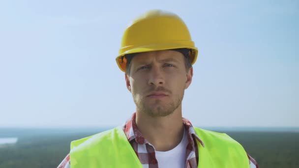 Ervaren mannelijke bouwer in veiligheidshelm kijkend naar camera, kwalitatieve service — Stockvideo
