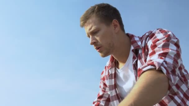 Испуганный молодой человек смотрит вниз с открытой террасы, страх высоты, акрофобия — стоковое видео