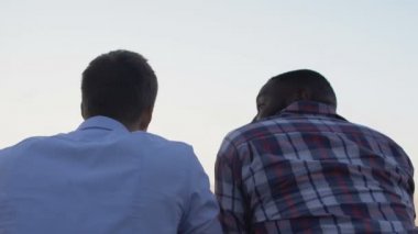 Erkek arkadaşlar şehir altyapısına balkondan bakıyorlar.