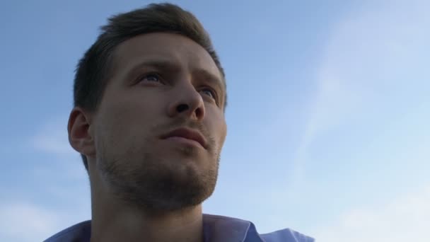 Hombre guapo contemplando el futuro en el fondo del cielo brillante, primer plano — Vídeo de stock