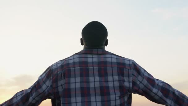 アフリカ系アメリカ人の男性が夕日、自由とインスピレーションを楽しんで手を広げて — ストック動画