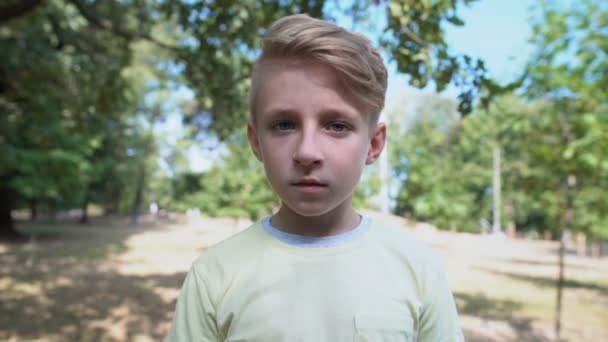 Shocked caucasian boy feeling overwhelmed standing in park, emotions concept — Stock Video
