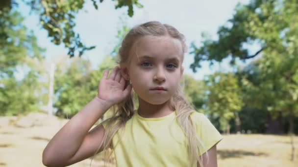 Дівчина торкається вуха, прослуховує плітки, проблема втрати слуху дитини, глухота Стокове Відео 