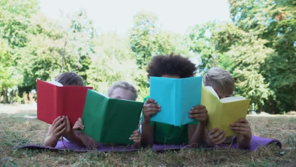 Kitap okuyan çocuklar, parkta yatan paspas, kitap severler kulübü, eğitim konsepti. — Stok video
