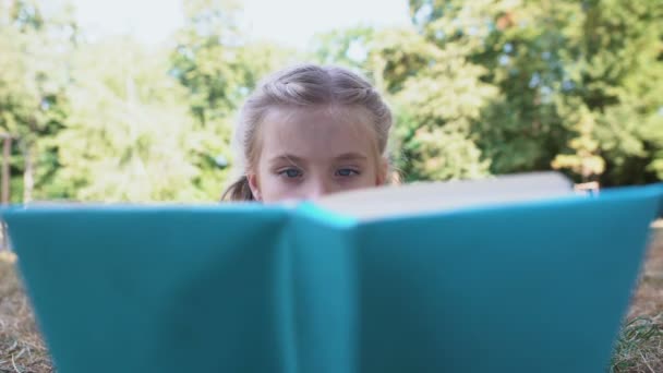 Ragazza che legge interessante libro avventuroso, sdraiato nel parco, concetto di tempo libero — Video Stock