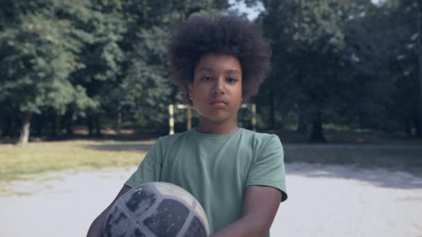 Сумний афроамериканський хлопчик з футболом на полі, немає друзів, расова дискримінація — стокове відео