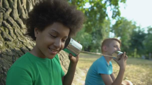 Felices amigos multiétnicos hablando a través de latas, feliz infancia sin artilugios — Vídeo de stock