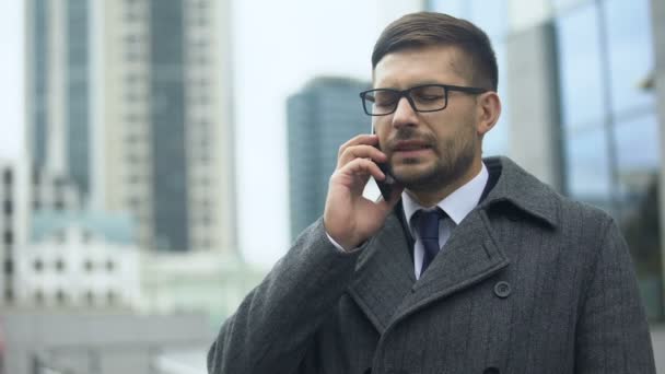 Businessman feeling pain in head talking phone outdoors, nervous tension, spasms — Stock Video