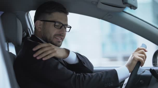 Sensación de dolor en el hombro del conductor sentado en el coche, esguince muscular, problemas de salud — Vídeo de stock