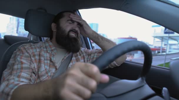 Hombre con camisa a cuadros que sufre migraña mientras conduce el coche, día estresante — Vídeo de stock