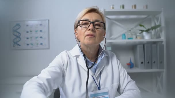 Verouderde vrouwelijke arts onderzoeken patiënt met stethoscoop schudden hoofd, slechte resultaten — Stockvideo