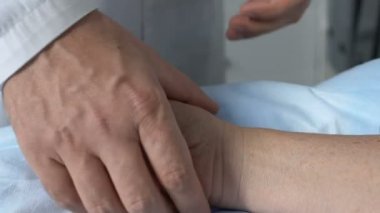 Doktor baygın hasta nabzını kontrol ediyor. Bileğe dokunuyor, hastaneye ilk yardım yapılıyor.