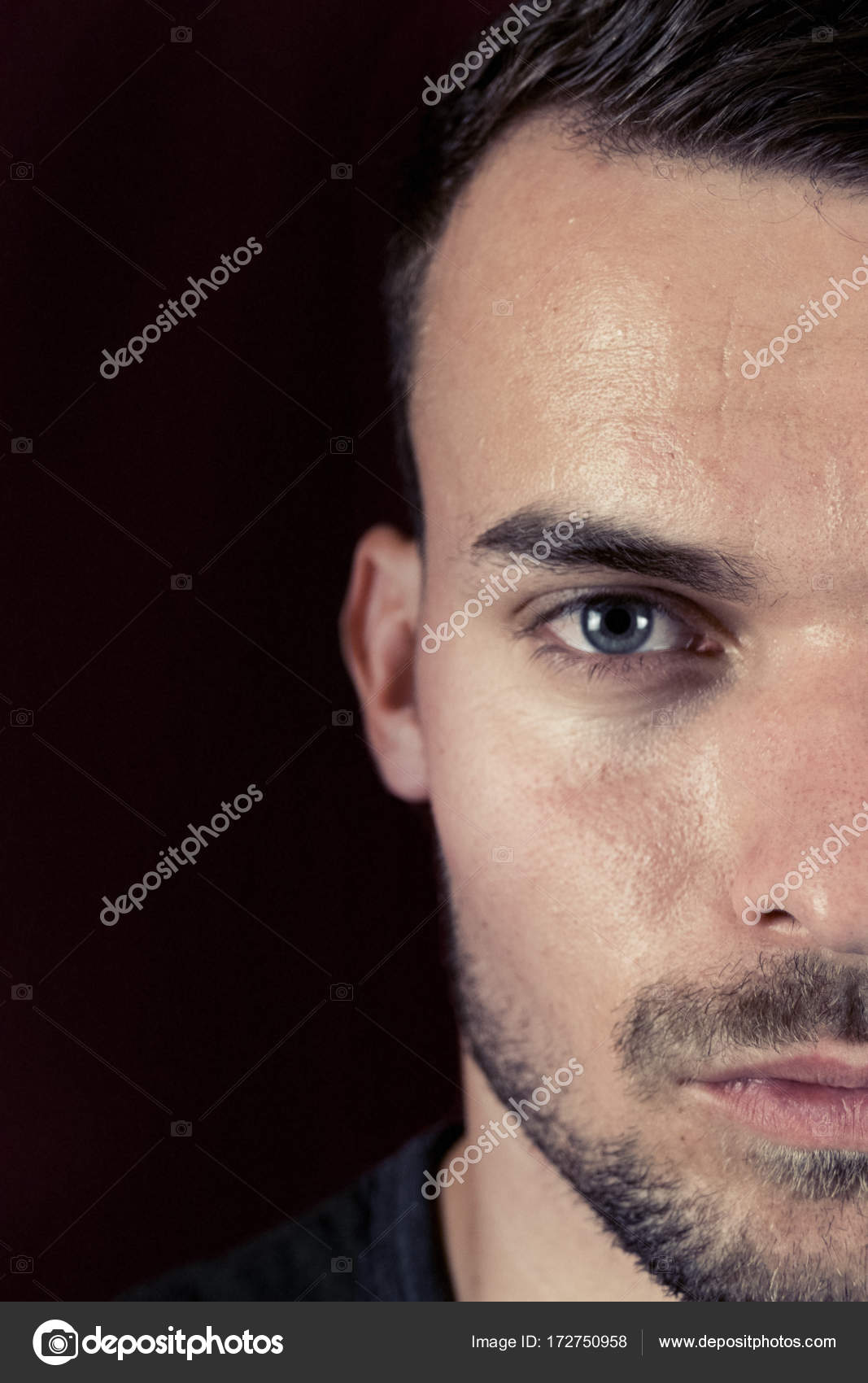 Portrait Of Beautiful Young Man With Green Eyes On Dark Black And Red Background Half Face