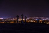 Stadtnacht in Nitra vom Aussichtspunkt auf dem Gipfel der slowakischen Stadt Nitra mit violettem Nachthimmel und Kreuzen. Innenstadt bei Nacht mit Gebäuden und Kirchen. Stadt bei Nacht mit Sternen