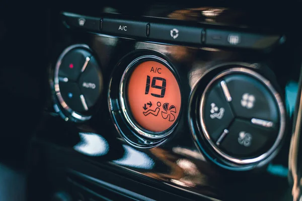 Mains de femme tournant système de climatisation de voiture. Bouton sur le tableau de bord à l'air froid dans une nouvelle voiture - panneau orange. Photo de la vue de la climatisation avec bouton de climatisation avec degrés Celsius - 19 . — Photo