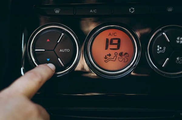 Mãos de mulher transformando sistema de ar condicionado do carro. Botão no painel ao ar frio no novo carro - painel cor-de-laranja. Foto da vista de controle climático com botão de ar condicionado com graus celsius - 19 . — Fotografia de Stock