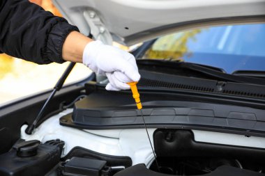 Hand pulling a car's dipstick. Checking engine oil step by step.