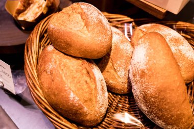 Klasik baget ekmeğinin, rattan bir sepetteki görüntüsünü kapat.