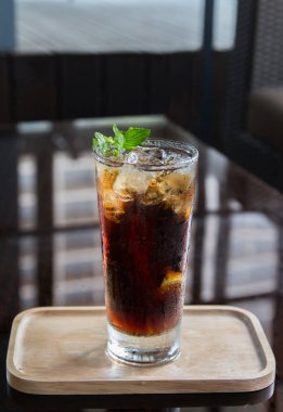 Long Island kokteyli, ahşap tepside ve siyah arka planda..