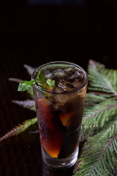 Long Island cocktail drink with mint leaf on a black background.Long Island cocktail drink with mint leaf and plant decoration
