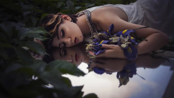 Beautiful brunette woman sleeping in a grass and flowers in the — Stock Photo, Image