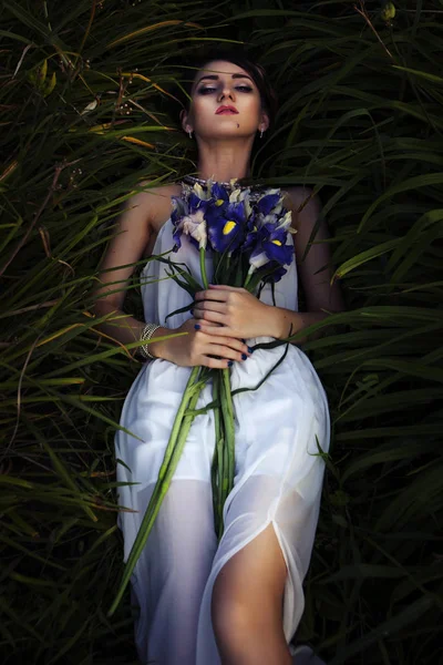 Όμορφη μελαχρινή γυναίκα στον ύπνο σε μια χλόη και λουλούδια για την — Φωτογραφία Αρχείου
