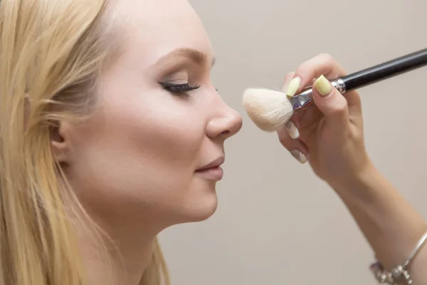 Brunette make-up artiest vrouw make up solliciteert met een blonde brid — Stockfoto