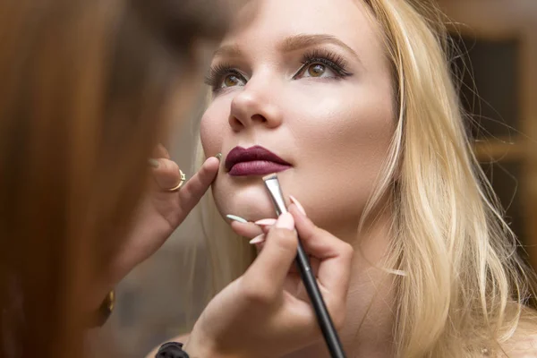 Bruna make up artista donna applicando il trucco per una bionda ibrida — Foto Stock