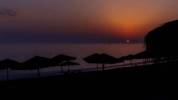 Warm red and yellow sky and sea, with silhouette of palms and lo — Stock Photo, Image