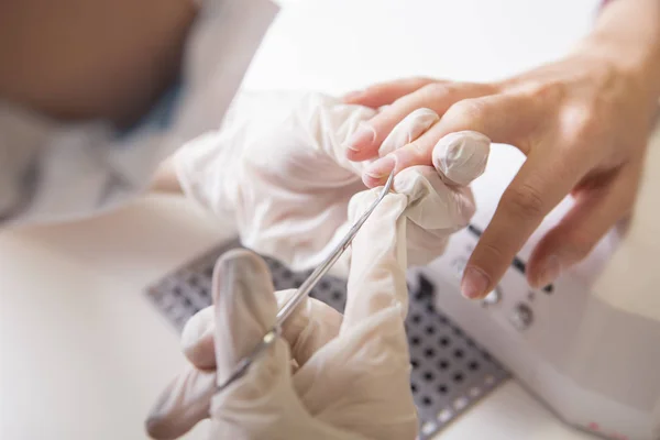 El maestro de uñas en guantes de goma hace manicura (cutícula de cuidado) en una w —  Fotos de Stock