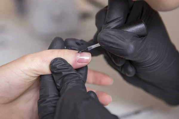 Maestro de uñas en guantes de goma aplicar gel laca laca en una mujer —  Fotos de Stock