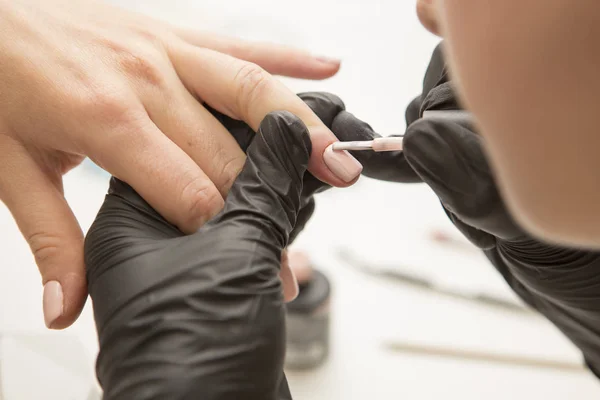 Maestro de uñas en guantes de goma aplicar gel laca laca en una mujer —  Fotos de Stock