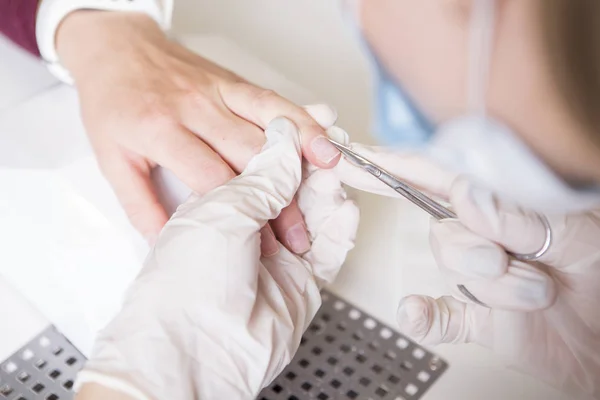 Meester in de rubber handschoenen make Nail manicure (zorg cuticula) op een w — Stockfoto