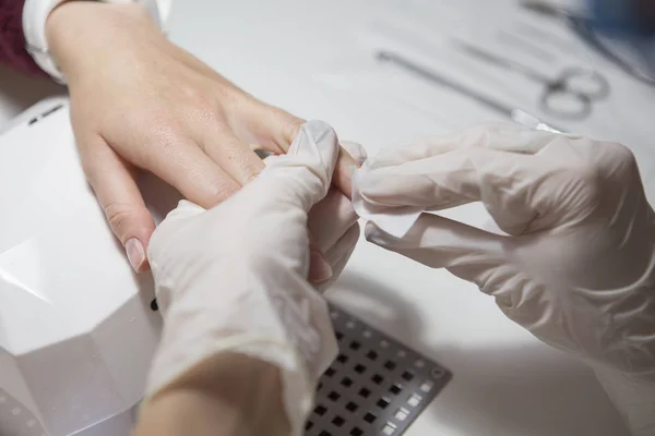 Meester in de rubber handschoenen make Nail manicure (zorg cuticula) op een w — Stockfoto