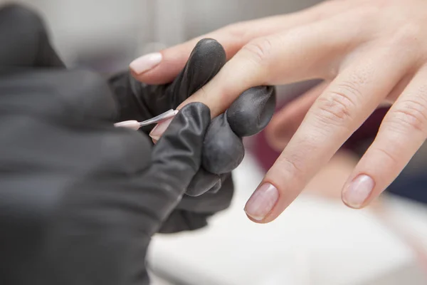 Мастер ногтей в резиновых перчатках наносит гель лак шеллак на женщину — стоковое фото