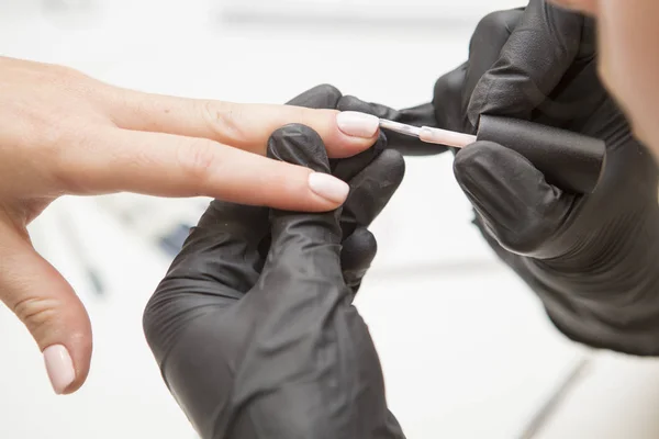 Maestro de uñas en guantes de goma aplicar gel laca laca en una mujer —  Fotos de Stock