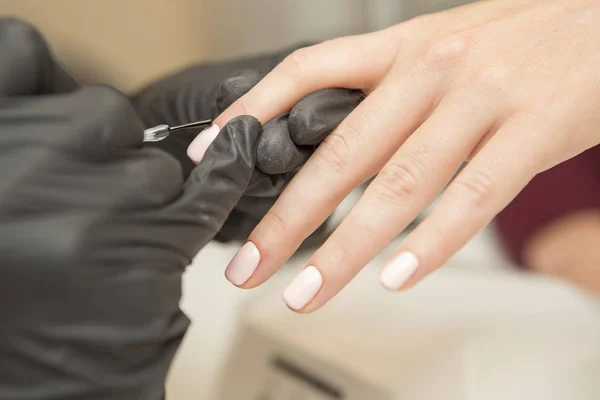 Mestre prego em luvas de borracha aplicar gel polonês goma laca em uma mulher — Fotografia de Stock