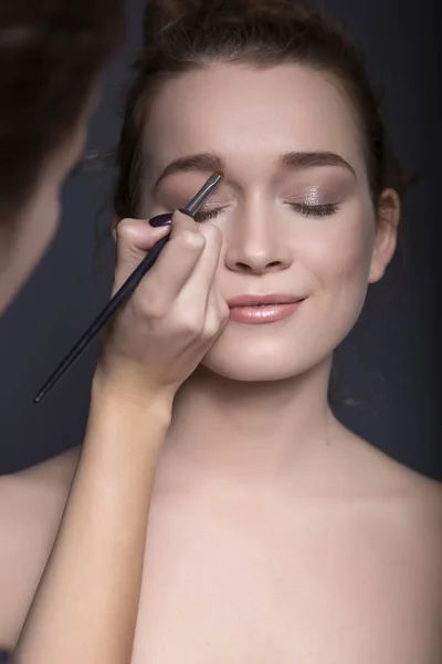 Maquillaje artista aplicando maquillaje hermosa morena caucásica wom —  Fotos de Stock