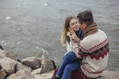Deniz sarılma yakınındaki bir rock plajda oturup mutlu düşünceli Çift